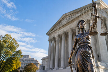 Statue de la déesse de la Justice devant le bâtiment de la Cour suprême des États-Unis sous un ciel bleu.