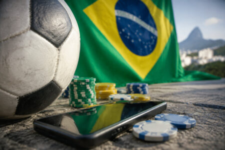 Ballon de football, jetons de casino et smartphone avec le drapeau brésilien et le mont du Pain de Sucre en arrière-plan.